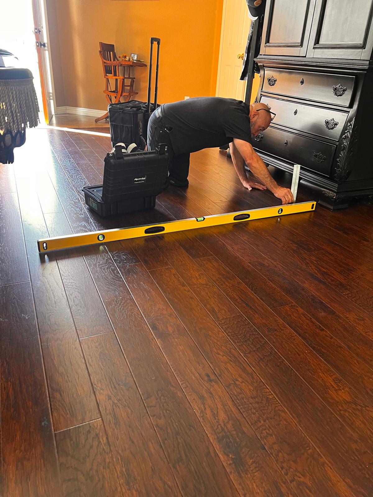 Nick Perez on site, measuring a hardwood floor with a level